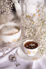 white still life with cheesecake and gypsophila and cup of tea, light and airy