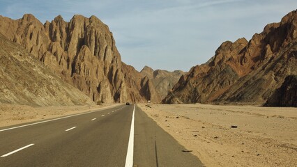 An empty road that runs deep into the mountains in the Sahara Desert of Egypt