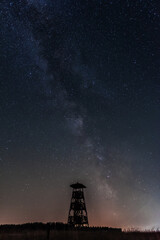 the silhouette of an observation tower at night with a starry sky in the background