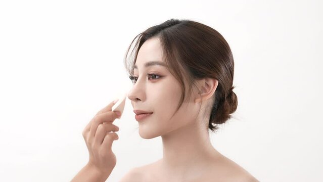 Beauty concept of 4k Resolution. Asian young woman applying face powder foundation on a white background.