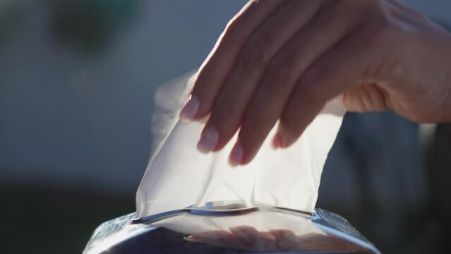 Closeup view slow motion 4k stock video footage of manicured female hand taking two white paper tissues outdoors in street restaurant