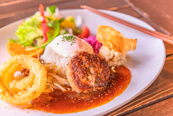 Hawaiian Loco Moko rice plate with vegetables, an hamburger, a fried egg and fried onion rings on a plate with chopsticks in a Japanese restaurant of Futamigaura beach of Fukuoka in Kyushu.