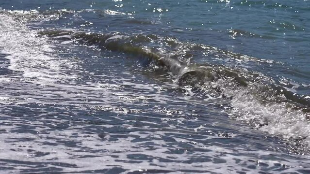 Blue sea water with white foam splashing slowly on sunny tropical beach. Natural water 4k slow motion video bakcground