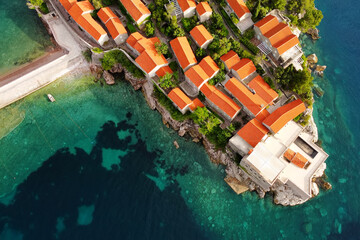 Amazing sunset aerial top drone view of Sveti Stefan island with historical town. Top down view of picturesque little island in Adriatic Sea located in Montenegro. - obrazy, fototapety, plakaty
