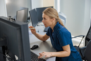 Nurse on Duty makes announcement into microphone sitting at Reception Desk. High quality photo