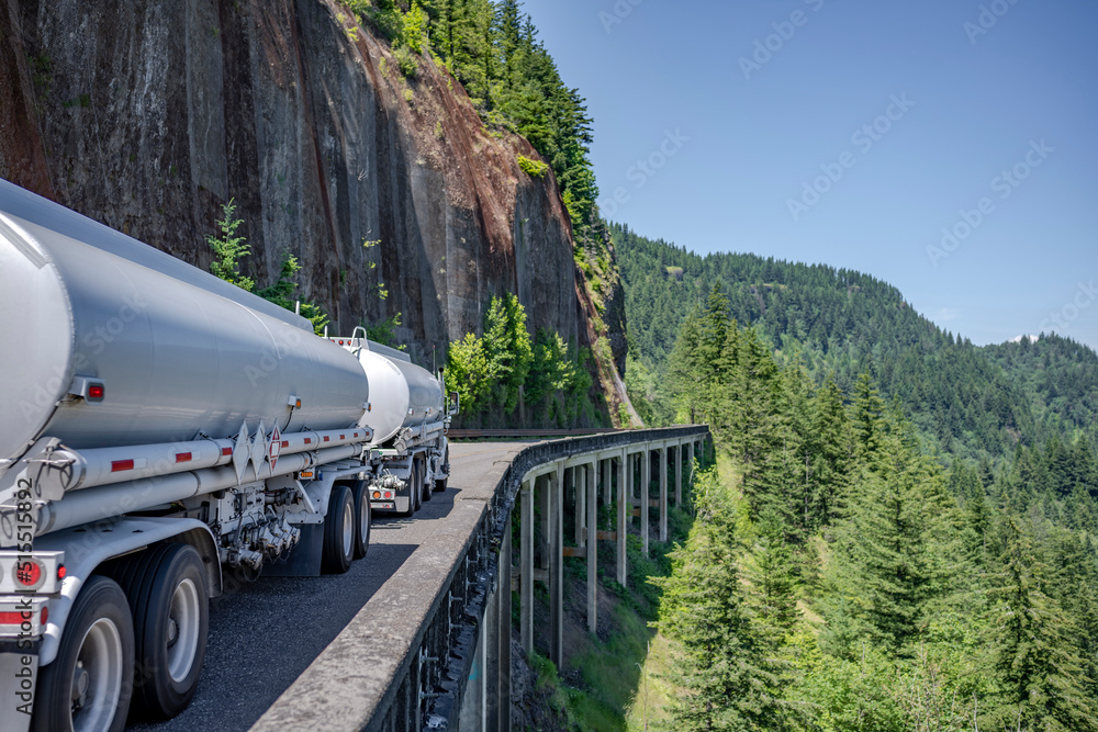 Wall mural day cab big rig semi truck transporting liquid cargo in two tank semi trailers running on the windin