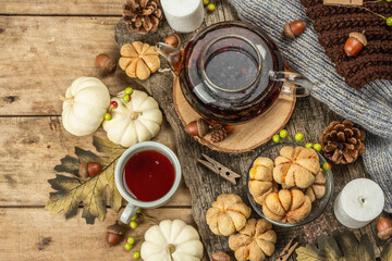 Autumn tea concept. Cookies with pumpkin puree, black tea in a glass teapot, fall decor