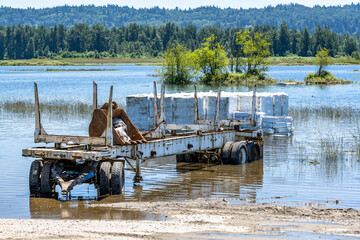 Sunken old rusty semi trailer and an unloaded stacked cargo standing in water after a Columbia...