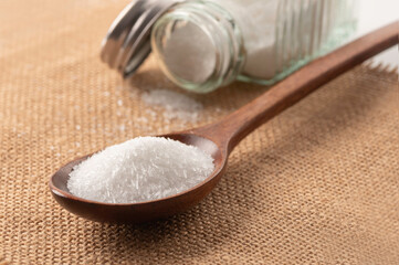 Monosodium glutamate in spoon on sackcloth background.
