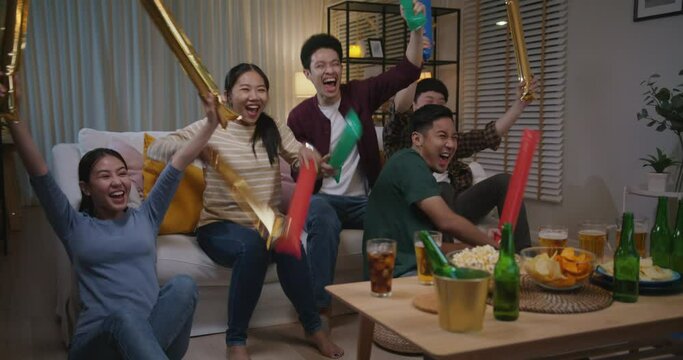 Group of young adult friend man and woman asia people sit at sofa couch joy night party fun game world cup live TV at home eat snack bowl drink beer bottle glass jump mad happy win exult face