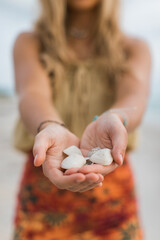 young woman holding white seashells on the beach
