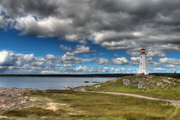 Fototapeta na wymiar historic lighthouse with dramatic clouds and road