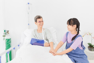 Obraz premium Asian children holding hand of patient in hospital, she visit and care patient, elderly health care, hand in hand