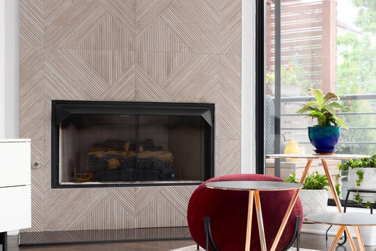 Detail shot of a fireplace with a pattern tile, contemporary furniture and a large window.