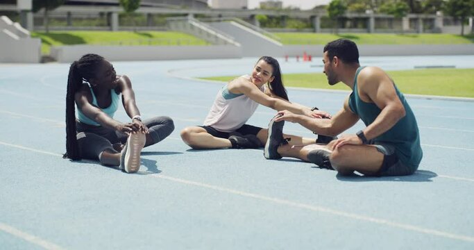 Diverse group of marathon runners talking while getting ready for a race in a stadium. Young athletes stretching their legs as a warmup exercise to prevent injury during training on a sports track.