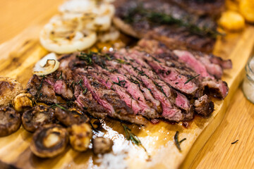 Grilled barbecue beef steak with spices on cutting board in kitchen.