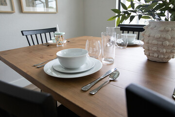 Fototapeta premium White table setting on wood table with black chairs and plant on table
