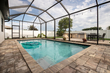 Fototapeta na wymiar Backyard veranda pool with kitchen/grilling station and patio furniture