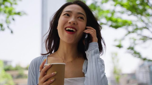 Close up of attractive young asian businesswoman walking in the city talking on mobile phone smile happy