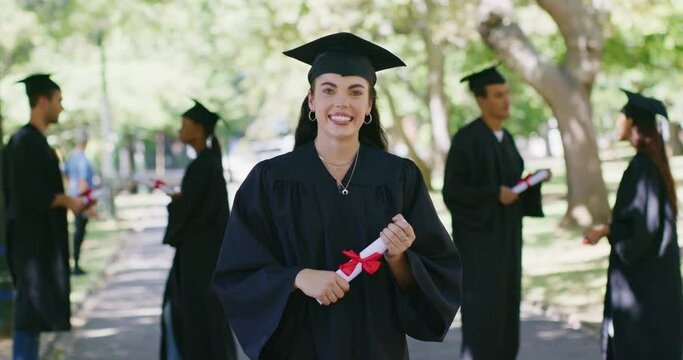 Portrait of a female university or college graduate standing outside with her degree or diploma on graduation day. Young woman in mortarboard and gown celebrating success in education and studies