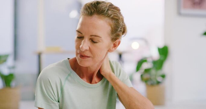 Senior woman with cramp rubbing her neck and shoulder. Face of a stressed, tired and anxious lady unable to concentrate while feeling sore from chronic pain. Worried mature female with stiff muscles