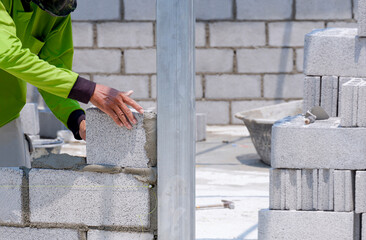 Cropped image of Asian builder worker making interior brick wall inside of house construction site