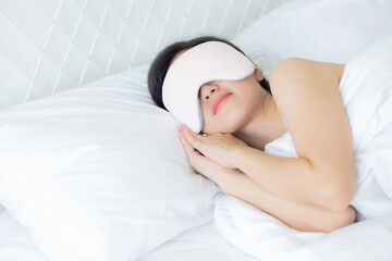 Beautiful young asian woman wearing cover eye and sleeping on bed with head on pillow comfort and happiness in the bedroom at home, girl with relax and leisure for wellness, lifestyles concept.