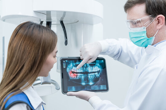 Caucasian male dentist hold digital tablet and explaining tooth problem. 