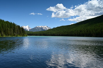 Snow-capped mountains behind Stantion Lake in Great Bear Wilderness, Montana on sunny summer day.