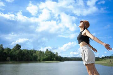 Obraz premium Asian Girl in green meadow of nature river happy holiday. Pleasure scene.Young woman watching landscape, posing outdoor. Active lifestyle concept. Arms up.