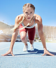 Serious female athlete at the starting line in a track race competition at the stadium. Fit...