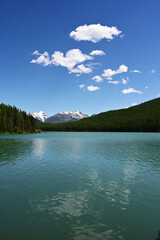 Snow-capped mountains behind Stantion Lake in Great Bear Wilderness, Montana on sunny summer day.