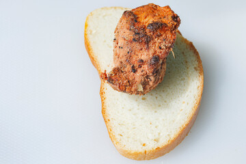 a sliced piece of bread with a piece of pork meat cooked over a fire