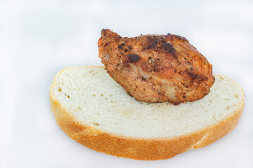 a sliced piece of bread with a piece of pork meat cooked on a fire, close-up