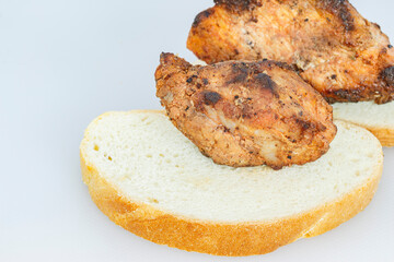 a sliced piece of bread with two pieces of pork meat cooked over a fire, close-up