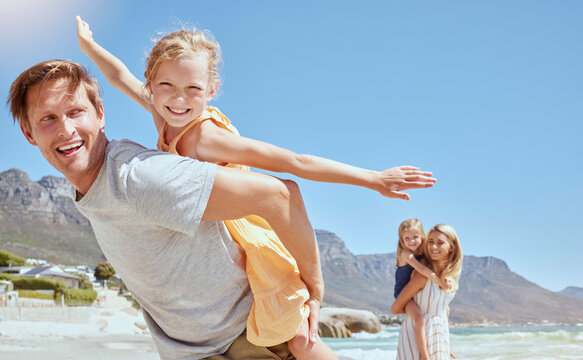 Smiling family with daughters on the beach. Happy man and woman bonding with young adorable girls on holiday. Cute siblings pretending to fly while being carried by their mother and father outside