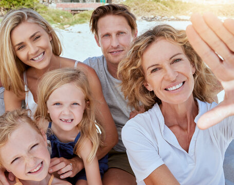 Portrait of a relaxed family relaxing and bonding at the beach. Two cheerful little girls spending time with their parents and grandmother on a beach vacation. Family taking a selfie together