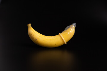 condom and banana on the black color, sex education concept