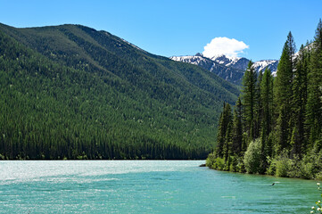 Snow-capped mountains behind Stantion Lake in Great Bear Wilderness, Montana on sunny summer day.