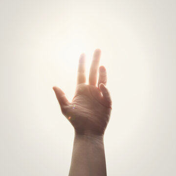 A hand is touching a ray of light of hope for a religious worship message about faith and God.
