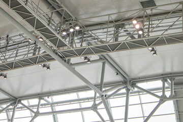 Ceiling with bright lighting in a modern warehouse, shopping center building, airport or other commercial real estate object. Directional LED lights on rails under the ceiling