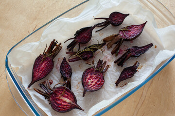 Glazed and roasted young beets on a piece of baking paper, baked baby beets on the wooden...