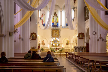 Minsk, Belarus - June, 30, 2022 View of the altar of the Church of St. Simeon and St. Helena in Minsk, parishioners sit on benches in the temple - obrazy, fototapety, plakaty