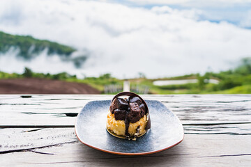 Delicious black chocolate cake placing on wooden table in the background beautiful landscape.