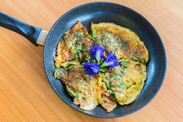 The omelet mix with climbing wattle, Acacia,  Blue Pea, Butterfly Pea, Thai vegetable herb on the frying pan.