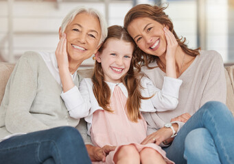 Family generations of females sitting together and looking at the camera. Portrait of an adorable little girl bonding with her mother and grandmother at home. Enjoying a visit with her granddaughter