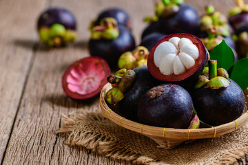 Fresh Mangosteen in bamboo basket and on old wood baclground.