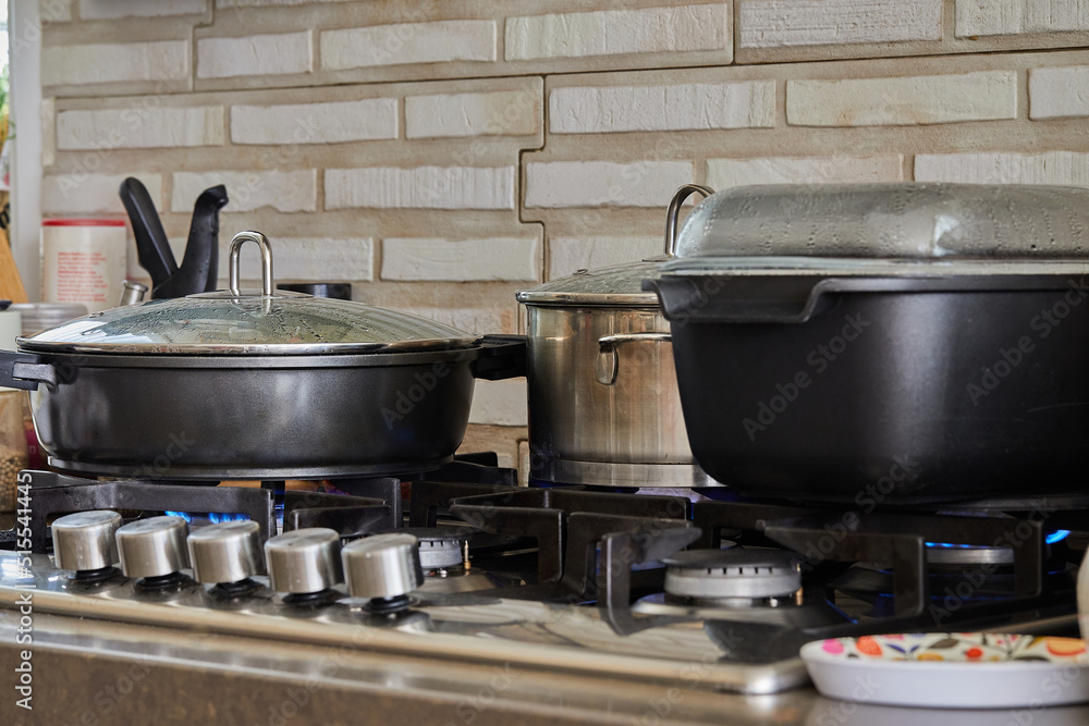 Poster Preparing food in frying pan and casseroles on the gas stove in the kitchen. Home cooking concept