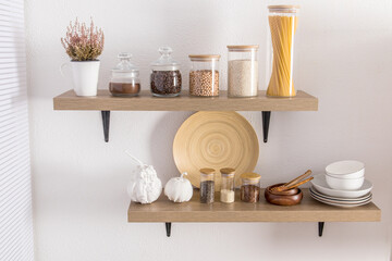 open wooden shelves with various glass jars with a wooden lid filled with spices, coffee, spaghetti. stylish decor in the modern kitchen. front view.