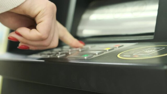 A young woman iusing an ATM machine to get money from her credit card.